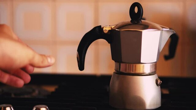 Man's hand turns off the stove takes a moka.
Coffee moment in an Italian home. Coffee drinkers and moka pot.