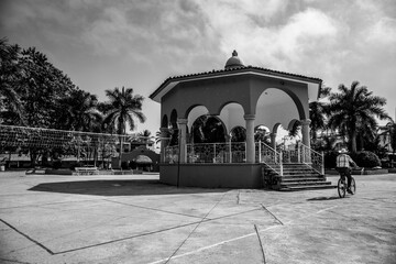 Obraz premium A man rides his bike in front of the kiosk in the town square in Lo de Marcos, Mexico.