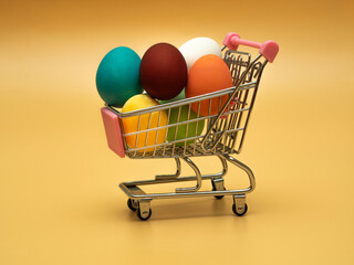 Several multicolored colored, boiled chicken eggs in a shopping cart (trolley). The concept of buying or selling decorated products and food for Easter.