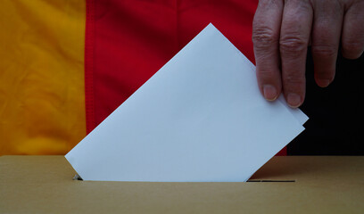 Eine Frauenhand steckt einen weißen Zettel in eine Box