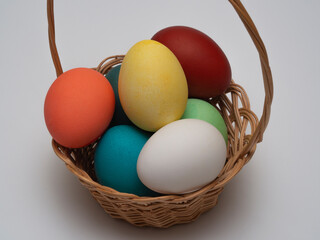 Multicolored, painted boiled chicken eggs in a wicker wooden, rustic basket. Traditional elements of a happy Orthodox or Catholic Easter.