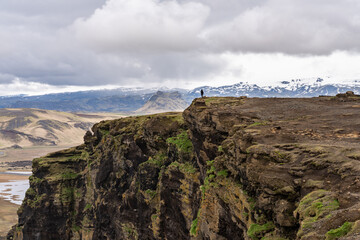 Fototapeta na wymiar Scenery from Dyrhólaey View Point in South Iceland with a man alone in the distance standing at the edge of the cliff