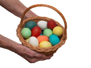 Old, elderly woman holds in her hand a multicolored, painted boiled chicken eggs in a wicker wooden, rustic basket. Traditional elements of a happy Orthodox or Catholic Easter.