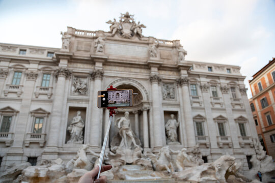 Smart phone on a stick taking picture of Fontana di trevi in Rome, Italy. Selective focus.