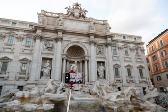 Smart phone on a stick taking picture of Fontana di trevi in Rome, Italy. Selective focus.
