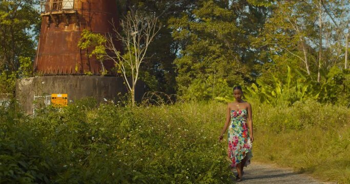 A young sexy girl walks along the flowers at the base of an abandoned military radar tracking station