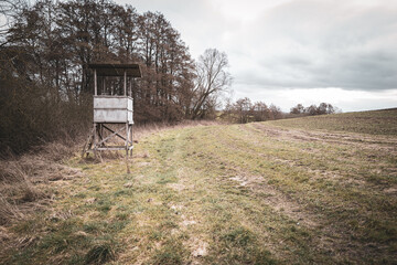 on a edge of a field stands a hunter's high and the sky is cloudy