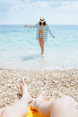 woman in blue checked shirt walking by sea beach
