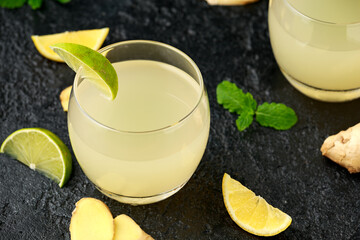 Ginger and lemon beer sparkling fizzy drink in glasses with lime wedges on the side