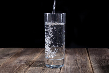 clean water pours a jet into a transparent glass