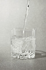 clean water pours a jet into a transparent glass