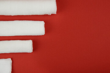 On a red background, three bandages and medical wipes. Top-down layout