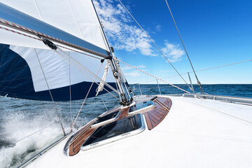 White sailing boat and bright blue sea and sky with water spraying