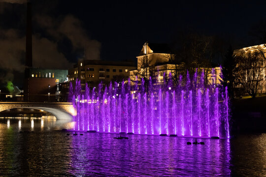 Violet light in a fountain with city landscape in background
