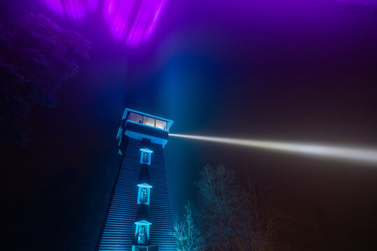 Wooden observation tower against lighted sky at night