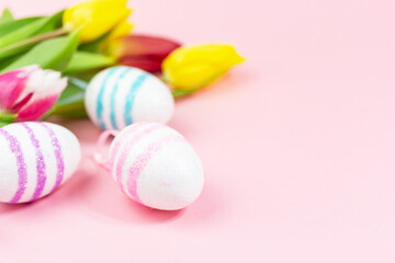 Easter painted eggs with tulips on a pink background. Copy space. Easter celebration concept