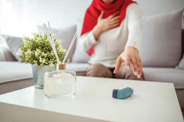 Muslim woman in hijab using inhaler at home, suffering breathing problem. Daily Life of a Person...