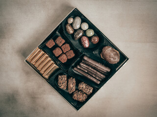 Different delicious chocolate candies on black table, flat lay, top view