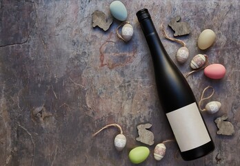 Top view of wine bottle with blank label and Easter eggs on table. Wine bottle mockup. Copy space for text.