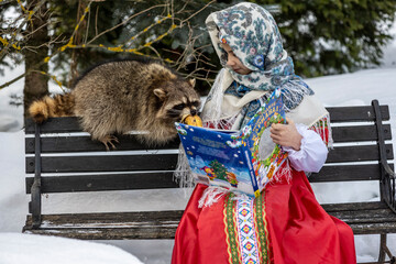 Obraz premium beautiful girl in a red sundress plays with a gray raccoon in a winter park