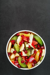 Fresh fruit salad cup made of juicy fruits on a black background.