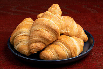 A pile of fresh baked butter croissants on a blue plate

