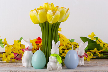 A tulip-shaped candle with Easter eggs, Easter bunny and a bouquet of flowers.