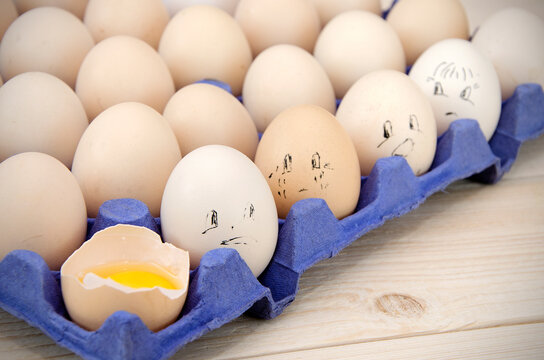 funny image drawings on eggs in a package and a broken egg