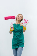 A young girl poses with a pink roller before painting a white wall. Repair of the interior.