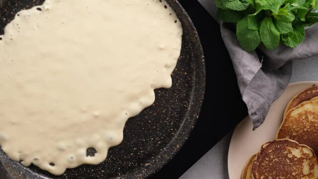 Frying thin crepe on a pan. Blini, french crepes cooking process, top view