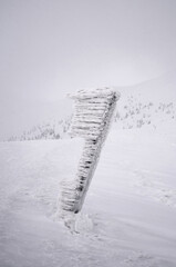 Obraz na płótnie Canvas Snow covered signpost on the mountainside.