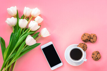 Cup of coffee, chocolate chip cookies, smartphone and white tulips on pink background, top view. Women's day or Mother's day concept. Flat lay, copy space