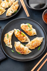 Delicious gyoza dumplings fried on a on black plates  with soy sauce
