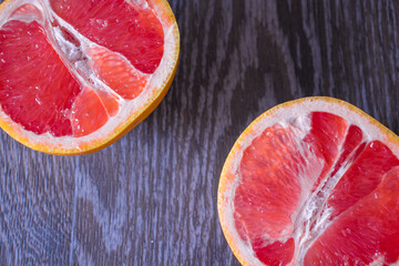 Two halves of grapefruit on a wooden surface close up