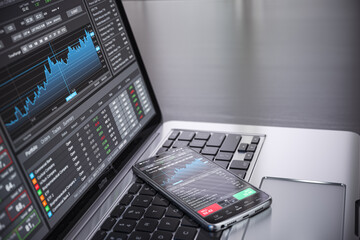 Stock exchange market concept. lLaptop and smartphone with stock trader application, graphs and diagrams on screen.