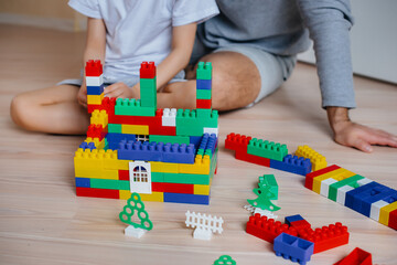 A little boy together with his father is played by a constructor and builds a house. Construction of a family home.