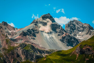 Mountains with some rocks falling down making a lot of dust