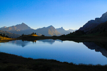 Fototapeta na wymiar reflection in a blue lake in the mountains with high peaks around the calm water