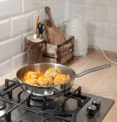 cooking meatballs in tomato sauce with vegetables in the kitchen in a frying pan