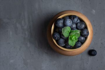 blueberries in a clay pot on a concrete background , top view