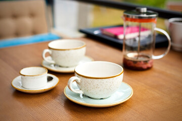 empty leftover tea cups and teapot on wooden table in cafe