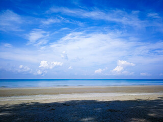 The bright blue sky and the bright white clouds, the beach and the clear blue sea in the daytime