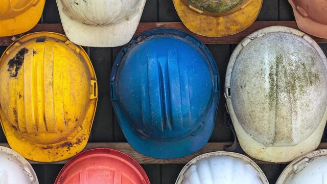 Horizontal pan of old and worn colorful construction helmets