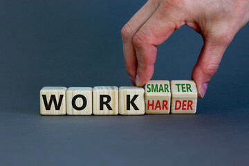 Work harder or smarter symbol. Businessman turns wooden cubes and changes words 'work harder' to 'work smarter'. Beautiful grey background, copy space. Business and work harder or smarter concept.