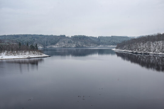 Photo of the smooth surface of the river framed by snow-covered banks