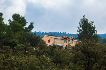 Fototapeta na wymiar Country house, in the middle of a Mediterranean forest, with a cloudy sky. 