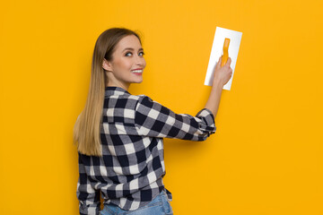 Young Woman Posing With Finishing Trowel On Orange Background. Concept photo.