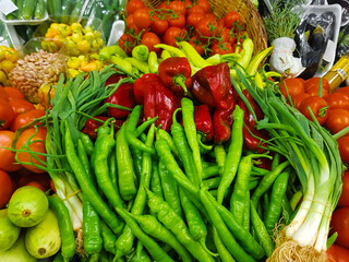 Vegetables on the market peppers, onions, tomatoes, zucchini, eggplant, greens.