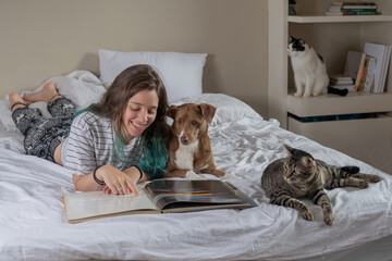 tennager with a book and pet on the bed in a bedroom
