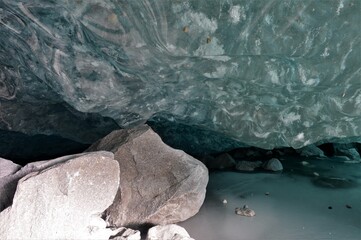 Glacier grotto with blue clear glacier ice and stones